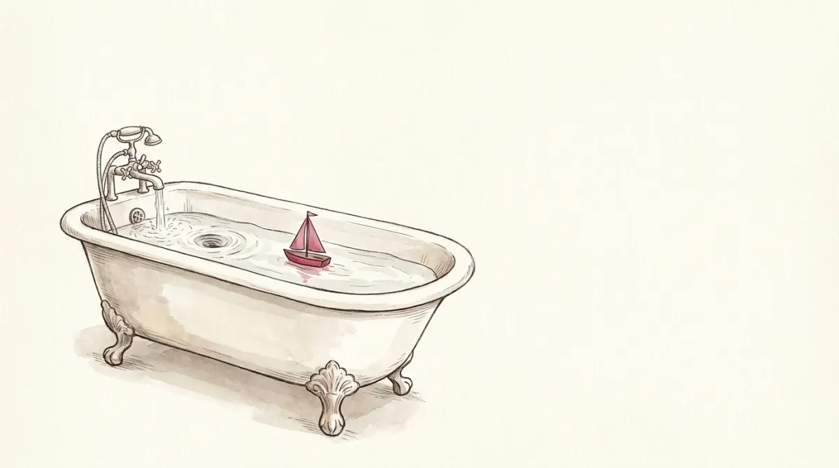 A claw-foot bathtub with the faucet running and the drain open, a small rose toy sailboat floating